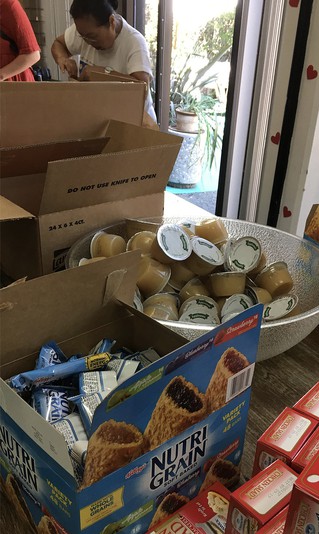 Volunteers prepare brown bag food items for Lifted Spirits' guests