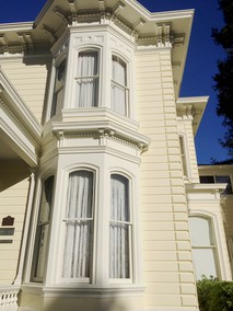 This close-up of the house shows the brackets, cornices, and curved windows typical of Italianate-style Victorian houses